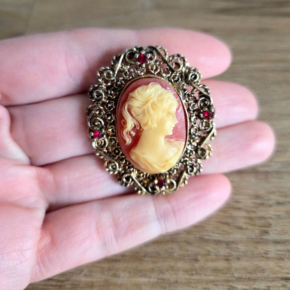 Vintage gold tone metal carved woman profile cameo with red rhinestones.